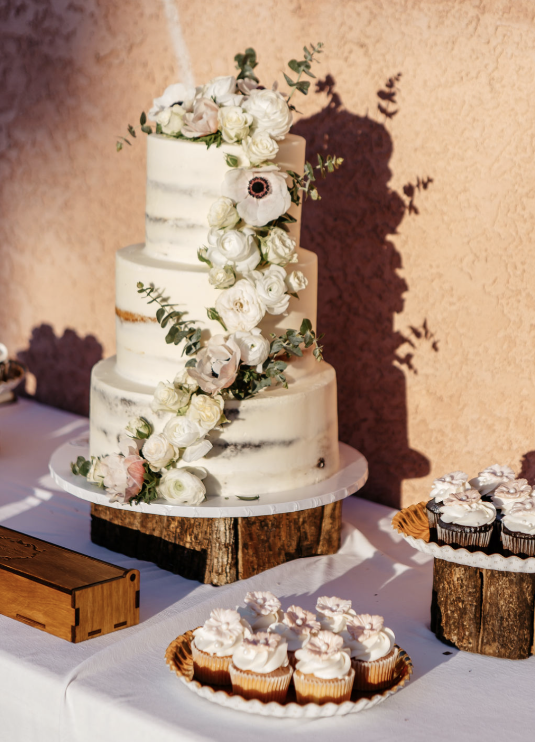 A three tier wedding cake dressed with fresh flowers